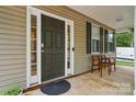 Covered porch with seating for two, decorative shutters, and a dark paneled front door at 9856 Caldwell Depot Rd, Cornelius, NC 28031