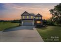 Two-story home with large driveway at dusk; features include white siding, stone accents, and covered entry at 1308 Austin Chaney Rd, Wingate, NC 28174