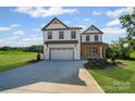 Newly constructed two-story home with white siding, stone accents, covered entry, and expansive driveway at 1308 Austin Chaney Rd, Wingate, NC 28174