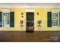 Welcoming front porch with a charming screen door and decorative floral arrangements on small tables at 14105 Garden District Row, Huntersville, NC 28078