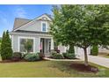 Inviting front exterior with manicured landscaping, covered entry, and attached two-car garage at 16034 Rushwick Dr, Huntersville, NC 28078