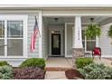 Welcoming front porch with stone accents, featuring a decorative hanging fern and American flag at 16034 Rushwick Dr, Huntersville, NC 28078
