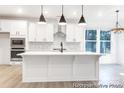 Modern kitchen with white cabinets, stainless steel appliances, a spacious island, and stylish pendant lighting at 236 Wheatfield Dr # 102P, Statesville, NC 28677