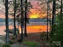 Picturesque lake view with a dock at sunset, framed by trees, offering tranquility and natural beauty at 258 Patterson'S Bridge None, New London, NC 28127