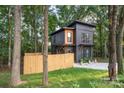 Charming two-story home with gray siding, natural wood accents, surrounded by lush greenery and a wood fence at 411 Granby Cir, Charlotte, NC 28217