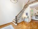 Bright entryway with hardwood floors, staircase with iron spindles, and views into the living spaces at 5816 Valley Stream Trl, Waxhaw, NC 28173