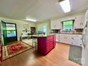 Functional kitchen featuring white cabinets, a red island and wood floors at 1229 Rocky Face Church Rd, Taylorsville, NC 28681
