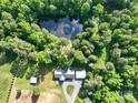 Aerial view of house nestled among lush trees including pond and outbuildings at 16132 Mclester Rd, Oakboro, NC 28129