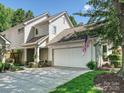 Charming home with garage showcasing an American flag, manicured lawn, and lovely trees in a vibrant neighborhood at 17732 Kings Point Dr, Cornelius, NC 28031