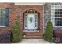 Inviting front entrance with brick archway, a decorative door, and manicured shrubbery enhancing curb appeal at 18118 Pompano Pl, Cornelius, NC 28031