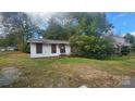 Exterior shot of a small, weathered home with boarded up windows and overgrown foliage at 210 Mahan Sw St, Concord, NC 28025