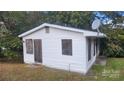 Exterior shot of a small, weathered home with boarded up windows and overgrown foliage at 210 Mahan Sw St, Concord, NC 28025