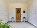 Inviting front entrance with a stained wooden door, wreath, and planters with flowers at 2517 Marlowe Ave, Charlotte, NC 28208