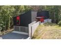 Contemporary home with sleek black exterior, red accents, driveway and a two-car garage at 386 Squirrel Ln, Lake Wylie, SC 29710