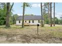 View of a white, single-story home with a wooden porch, nestled between mature trees at 403 W Charlotte Ave, Mount Holly, NC 28120