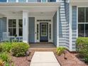 Inviting front porch featuring a navy door with sidelights, white columns, and lush landscaping around the walkway at 5005 Hedgebrook Ln, Waxhaw, NC 28173