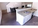 Modern kitchen featuring stainless steel sink, granite countertops, white cabinetry, and seamless flow to dining area at 6919 Ware Rd, Charlotte, NC 28212