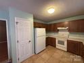 Functional kitchen featuring wooden cabinets, tile flooring, and essential appliances at 8819 Noah Helms Rd, Indian Trail, NC 28079
