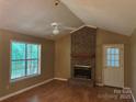 Cozy living room features a brick fireplace, vaulted ceiling, and large window with natural light at 8819 Noah Helms Rd, Indian Trail, NC 28079
