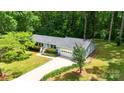 A bird's eye view of a light blue house with a green lawn and tall, dense trees surrounding the property at 144 Stoneybrook Rd, Salisbury, NC 28147