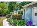 Close up of the side of a light blue house with white trim, lush green bushes, and vibrant purple flowers at 144 Stoneybrook Rd, Salisbury, NC 28147