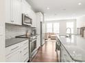 Modern kitchen with white cabinets, stainless steel appliances, granite countertops, and hardwood floors at 3007 Citizens Ln, Charlotte, NC 28205