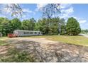 Wide angle view of the home featuring a gravel driveway with spacious yard and mature trees surrounding the property at 3585 Woodstream Dr, Maiden, NC 28650