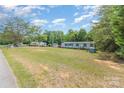 Exterior of home featuring a spacious lawn, mature trees and gravel road at 3585 Woodstream Dr, Maiden, NC 28650