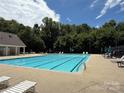 Beautiful swimming pool surrounded by lush greenery, lounge chairs, and shady umbrellas at 4240 Ladys Slipper Ln, Matthews, NC 28105