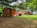 Brick home with a patio and green grass in a spacious backyard, surrounded by trees at 5628 White Store Rd, Wingate, NC 28174