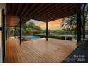 Spacious wooden deck with lounge chairs overlooking a serene lake and sunset view at 5930 Midsomer Rd, Charlotte, NC 28214