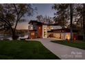 Modern lakefront home with sleek design, stone accents, and spacious three-car garage at 5930 Midsomer Rd, Charlotte, NC 28214