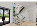 Floating staircase with glass railings and modern design, enhanced by natural light from large windows at 5930 Midsomer Rd, Charlotte, NC 28214
