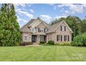 Charming brick home featuring a manicured lawn, lush landscaping, and a classic architectural design at 6057 Erie View Ct, Denver, NC 28037