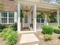 Inviting front porch with a pink door, white columns, hanging plants, and manicured landscaping at 9405 Gladden Hill Ln, Pineville, NC 28134