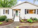 Close-up of a well-maintained home exterior with black shutters, a green door, and a lovely entry at 1723 Woodland Dr, Charlotte, NC 28205
