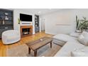 Cozy living room featuring hardwood floors, a brick fireplace, built-in bookshelves and a modern sofa at 1723 Woodland Dr, Charlotte, NC 28205