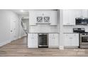 Eat in kitchen features white cabinets, a beverage cooler, modern lighting, stainless appliances, and hardwood floors at 3926 Litchfield Rd, Charlotte, NC 28211