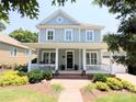 Inviting two-story home featuring a spacious front porch, manicured lawn, and vibrant landscaping at 5424 Morris Hunt Dr, Fort Mill, SC 29708