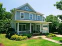 Inviting two-story home featuring a classic front porch, lush lawn, and mature trees at 5424 Morris Hunt Dr, Fort Mill, SC 29708