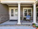 Cozy front porch with stone accents, white columns, and inviting decor with a chair, table, and potted plants at 705 Vintage Creek Dr, Matthews, NC 28104