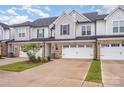 Attractive townhome showcasing brick details, a single-car garage, and lush green lawn at 9009 Odell Corners Nw Blvd, Concord, NC 28027