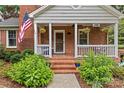 Inviting brick porch with American flag, hanging flower baskets, and seating at 1729 Kensington Dr, Charlotte, NC 28205
