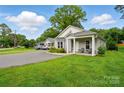 Charming single-story home with covered porch and cozy seating, complemented by a well-maintained front yard at 204 Craig St, Mount Holly, NC 28120