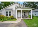 Charming single-story home with covered porch and cozy seating, complemented by a well-maintained front yard at 204 Craig St, Mount Holly, NC 28120
