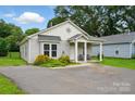 Charming single-story home with covered porch, cozy seating, neat landscaping, and a freshly paved driveway at 204 Craig St, Mount Holly, NC 28120