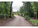 Gravel driveway leading into a property through a wooded area and a gated fence at 2310 Gill Jordan Rd, Chester, SC 29706
