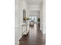 Hallway features hardwood floors, white wainscoting, and access to the living room with large windows at 3128 Spring Iris Dr, Denver, NC 28037