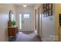 Inviting foyer with a stylish console table, oval mirror, decorative rug, and a bright, white front door with sidelight at 4710 Old Pageland Marshville Rd, Monroe, NC 28112