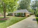 Side view of brick home with an expansive lawn, mature trees, and a long, paved driveway at 6116 Springhouse Ln, Charlotte, NC 28211